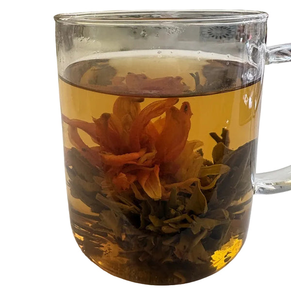 Clear glass mug filled with blooming tea flowers on a white surface